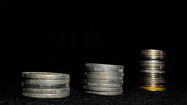 İş büyümesini simgeleyen para yığınları siyah arkaplanlı.