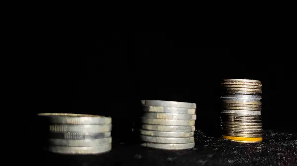 İş büyümesini simgeleyen para yığınları siyah arkaplanlı.