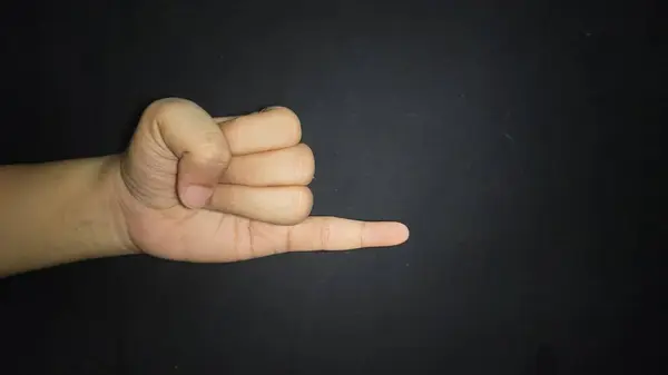 El, küçük bir parmak gösteriyor. Siyah arka planda izole edilmiş.