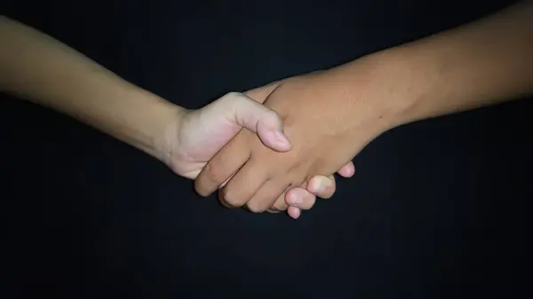 Bir erkekle kadın arasında eller titriyor. Siyah arkaplanda izole