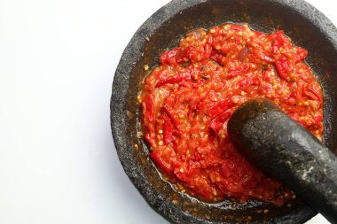 Endonezya 'dan gelen sambal ya da geleneksel biber sosu, taş havan ve tokmak kullanılarak yeni yapılmış, beyaz arka planda izole edilmiş..