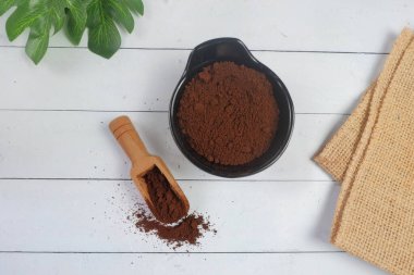 Kahve tozu ve kepçeli kase beyaz arka planda izole edilmiş.