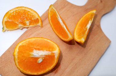 Taze kesilmiş portakallar tahta kesme tahtasının üzerinde dinleniyor.