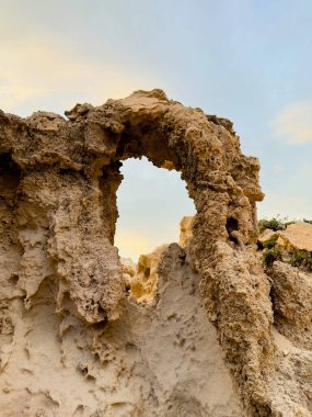 Natural Arch in Eroded Sandstone Cliff by the Coastline Shaped by Water and Wind clipart