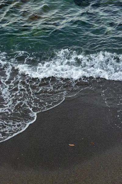 Hersonissos sahilinde kıyıya vuran temiz su bir turkuaz ve kahverengi gradyan oluşturur.