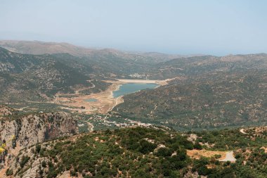 Lassithi Platosu 'nun manzarası Agios Konstantinos' un küçük su deposu ve çevresindeki yeşillikleri gösteriyor.