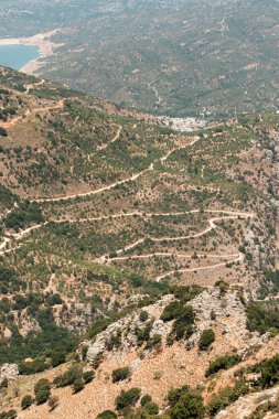 Lassithi Platosu Serpentine yolunu, Agios Konstantinos 'u küçük su deposunu ve çevresindeki yeşillikleri görüyor.