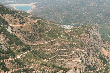 Lassithi Plateau landscape viewing the Serpentine road, Agios Konstantinos small water reservoir and surrounding greenery clipart