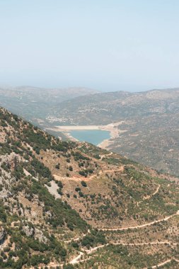 Lassithi Platosu 'nun manzarası Agios Konstantinos' un küçük su deposu ve çevresindeki yeşillikleri gösteriyor.