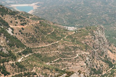Lassithi Platosu Serpentine yolunu, Agios Konstantinos 'u küçük su deposunu ve çevresindeki yeşillikleri görüyor.