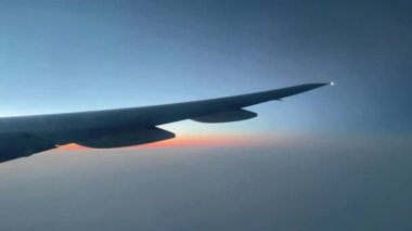 Ufuktaki gün batımı uçan bir uçak penceresinden görülüyor.