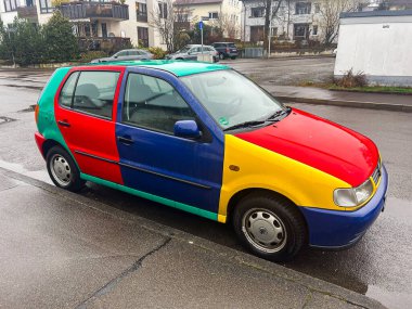 Stuttgart, Almanya... 12 Mart 2025, Volkswagen Polo Harlekin renkli araba komşu yol kenarına park edilmiş.