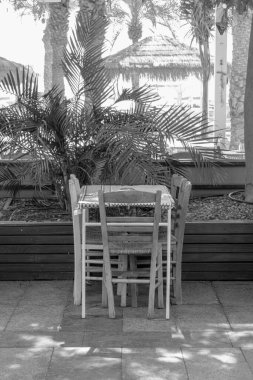 Eilat rıhtımında siyah beyaz beş kişilik boş bir masa.