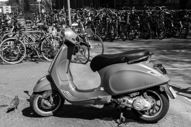 Ludwigsburg, Almanya... 12 Nisan 2025: Vespa Piaggio tarafından üretildi. Scooter siyah beyaz birçok bisikletin yanına park etmiş.