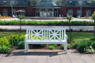 Frankfurt, Almanya 19 Nisan 2025, Frankfurt am Main 'deki Palmengarten Botanik Bahçesi' ndeki sera binasının önündeki beyaz bank.