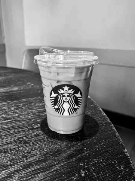 Nuremburg, Almanya - 2 Mayıs 2025 Starbucks soğuk kahve fincanı siyah beyaz ahşap masada oturuyor.