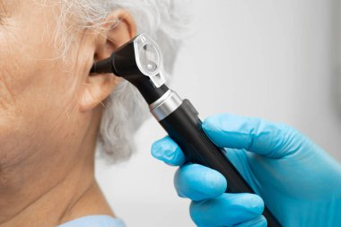 Otolaryngologist ya da ENT hekim doktoru yaşlı hasta kulağını otoskopla muayene ediyor, işitme sorunu var..