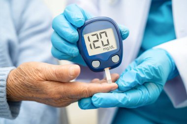 Diyabet tedavisinde kan şekeri seviyesini kontrol etmek için dijital glikoz ölçer kullanan Asyalı doktor.