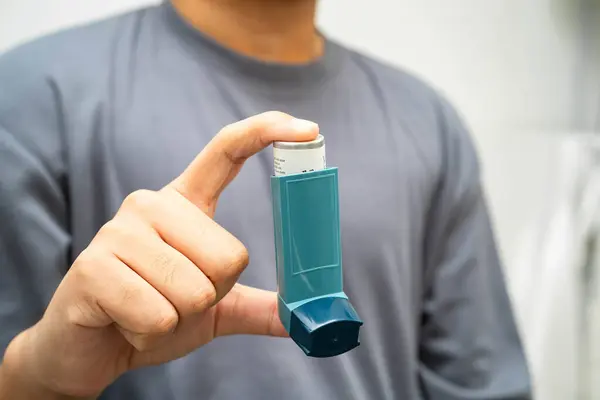Astım ve kronik obstrüktif akciğer hastalığı COPD, Asyalı genç adam ölçülü doz solunum cihazı kullanıyor..