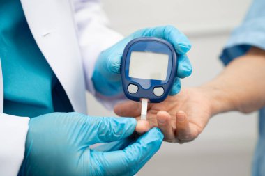 Diyabet tedavisinde kan şekeri seviyesini kontrol etmek için dijital glikoz ölçer kullanan Asyalı doktor.