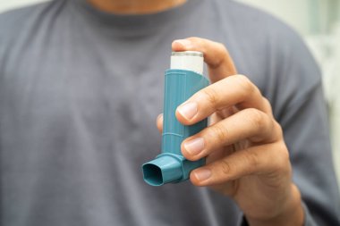 Astım ve kronik obstrüktif akciğer hastalığı COPD, Asyalı genç adam ölçülü doz solunum cihazı kullanıyor..