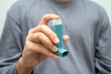 Astım ve kronik obstrüktif akciğer hastalığı COPD, Asyalı genç adam ölçülü doz solunum cihazı kullanıyor..