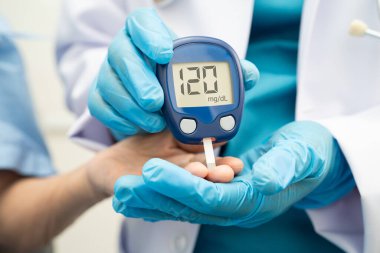 Diyabet tedavisinde kan şekeri seviyesini kontrol etmek için dijital glikoz ölçer kullanan Asyalı doktor.