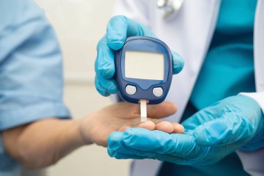 Diyabet tedavisinde kan şekeri seviyesini kontrol etmek için dijital glikoz ölçer kullanan Asyalı doktor.