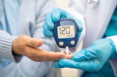 Diyabet tedavisinde kan şekeri seviyesini kontrol etmek için dijital glikoz ölçer kullanan Asyalı doktor.
