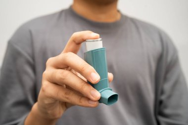 Astım ve kronik obstrüktif akciğer hastalığı COPD, Asyalı genç adam ölçülü doz solunum cihazı kullanıyor..