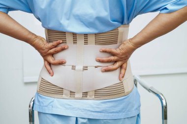 Bel ağrısı çeken Asyalı bir kadın. Hastanede yürüteç kullanıyor..