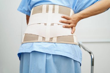 Bel ağrısı çeken Asyalı bir kadın. Hastanede yürüteç kullanıyor..