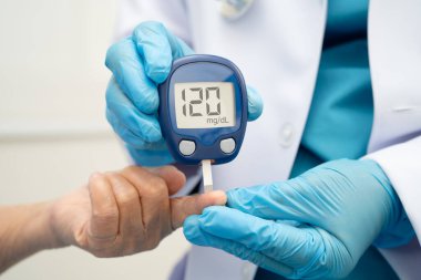 Diyabet tedavisinde kan şekeri seviyesini kontrol etmek için dijital glikoz ölçer kullanan Asyalı doktor.