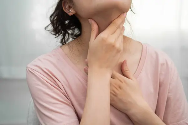 Tiroit bezi sorunu için boynuna ve boğazına dokunan Asyalı kadın..