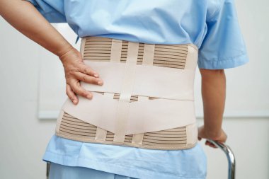 Bel ağrısı çeken Asyalı bir kadın. Hastanede yürüteç kullanıyor..