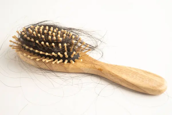 Tarak fırçasıyla beyaz arkaplanda saç kaybı.