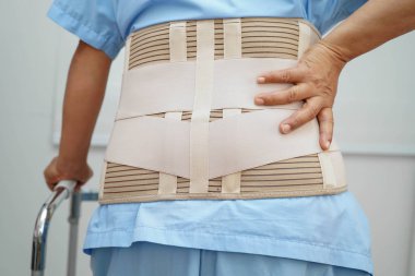 Bel ağrısı çeken Asyalı bir kadın. Hastanede yürüteç kullanıyor..