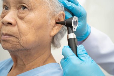 Otolaryngologist ya da ENT hekim doktoru yaşlı hasta kulağını otoskopla muayene ediyor, işitme sorunu var..