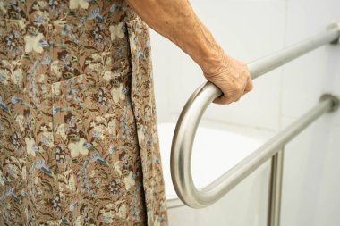 Asyalı yaşlı kadın hasta tuvalette tuvalet desteği kullanıyor..