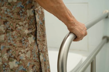 Asyalı yaşlı kadın hasta tuvalette tuvalet desteği kullanıyor..