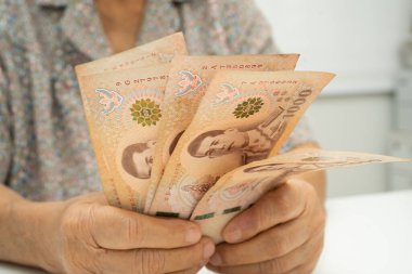 Tayland 'daki yaşlı bir hasta elinde para tutuyor. Yaşama ve tıbbi bakım masrafları..