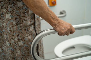 Asyalı yaşlı kadın hasta tuvalette tuvalet desteği kullanıyor..