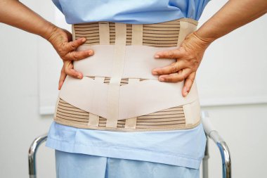 Bel ağrısı çeken Asyalı bir kadın. Hastanede yürüteç kullanıyor..