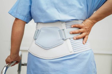 Bel ağrısı çeken Asyalı bir kadın. Hastanede yürüteç kullanıyor..