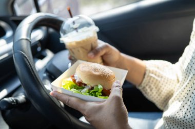 Asyalı kadın sürücü arabada hamburger yiyip, tutar, tehlikeli ve kaza riskini göze alır..