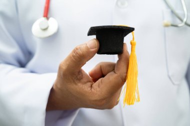 Hastanede mezun şapkası tutan Asyalı kadın doktor. Tıp eğitimi almış..