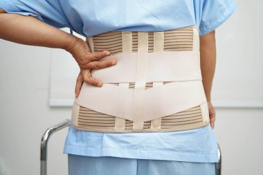 Bel ağrısı çeken Asyalı bir kadın. Hastanede yürüteç kullanıyor..