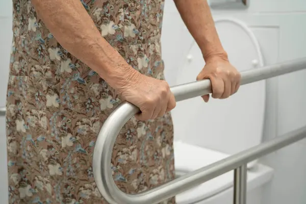 Asyalı yaşlı kadın hasta tuvalette tuvalet desteği kullanıyor..