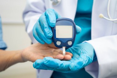 Diyabet tedavisinde kan şekeri seviyesini kontrol etmek için dijital glikoz ölçer kullanan Asyalı doktor.