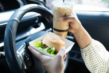 Asyalı kadın sürücü arabada hamburger yiyip, tutar, tehlikeli ve kaza riskini göze alır..